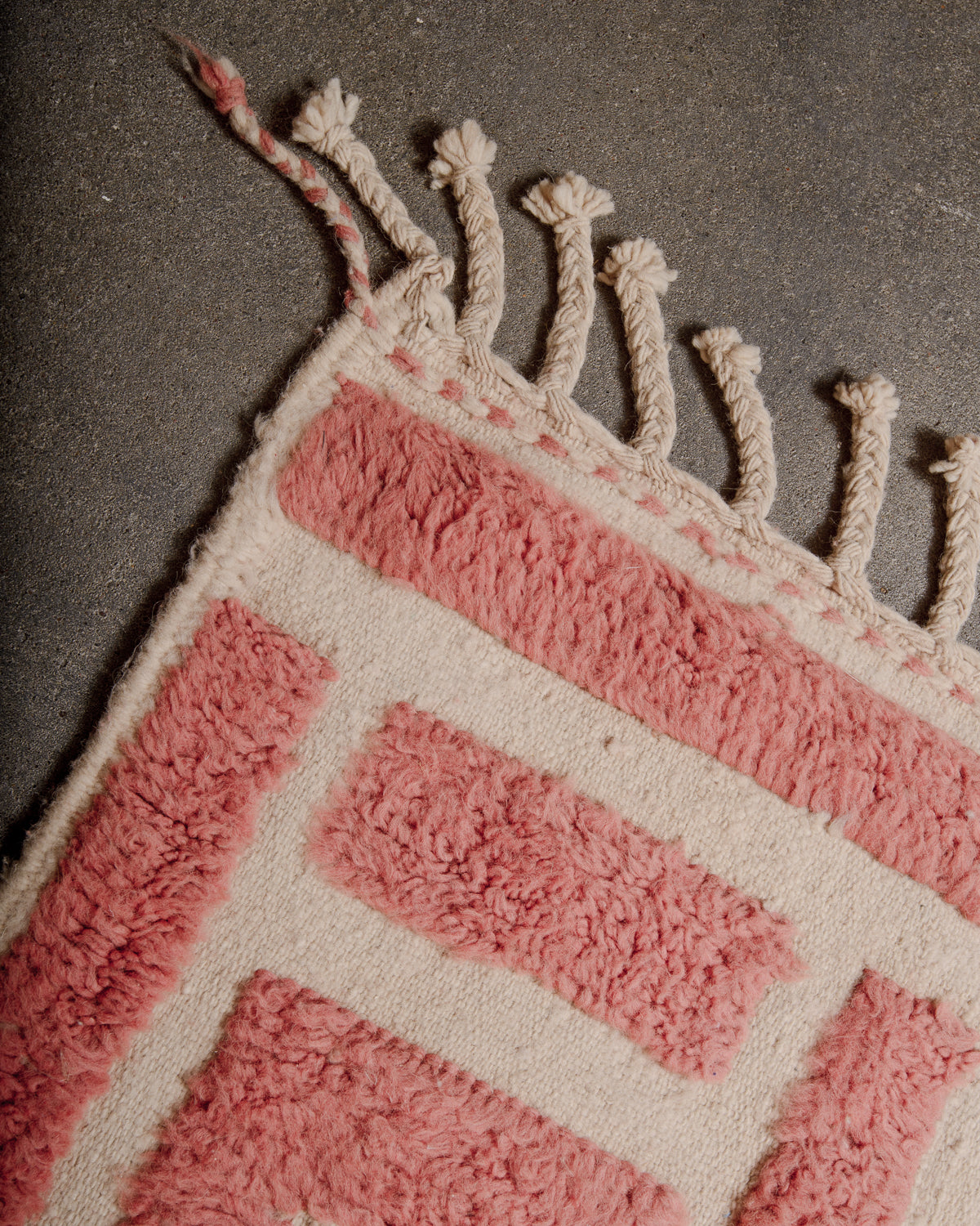 Natural wool tassels on Berberlin Special Edition rug with knotted wool pile in a soft dusty rose colour and flat woven base in natural cream.